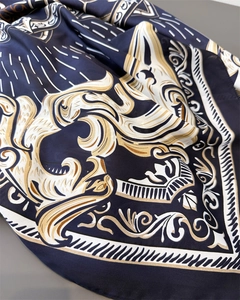 Detail of luxury silk scarf with baroque gold floral patterns on navy blue satin fabric