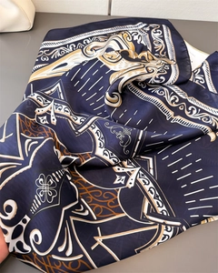 Detailed macro view of navy blue silk scarf with vintage gold and white pattern textures