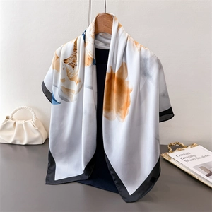 Detail of silk scarf featuring artistic yellow floral prints and elegant black borders