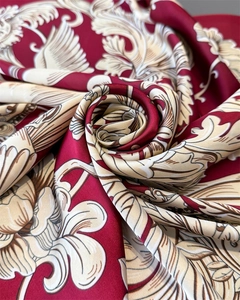Detailed close-up of luxurious red silk scarf with intricate baroque pattern and satin sheen