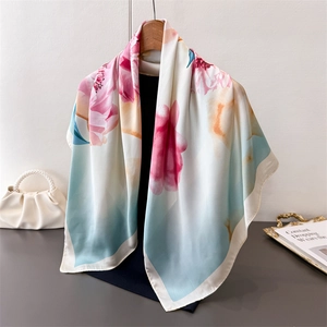 Detail of elegant peony print scarf with silky texture hanging on wooden hanger