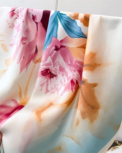 Detail of silk scarf with floral peony print featuring soft pink and orange color gradients