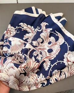 Close-up of silk-like scarf featuring navy baroque floral and bird patterns