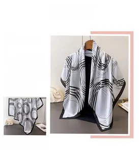 Close-up of geometric silk-like scarf with black abstract swirl patterns on white fabric