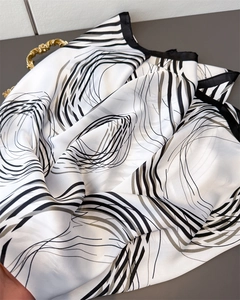 Close-up of geometric abstract printed silk scarf with smooth satin texture and black hem