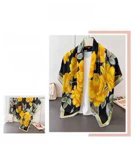 Detail view of large satin scarf featuring realistic yellow floral prints on black silk