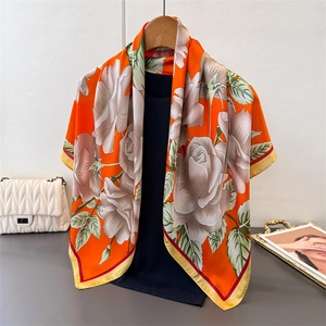Detail of satin floral scarf with orange base and white roses draped on a black top