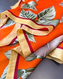 Detail of floral printed satin scarf with orange base and glossy silk texture