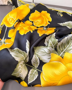 Detailed macro view showing the glossy satin fabric and yellow floral print on black scarf