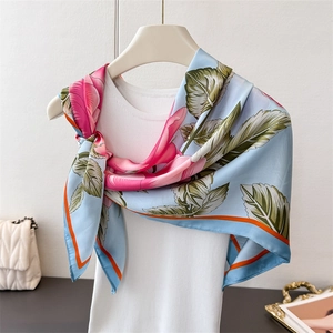 Detail of floral satin scarf with pink roses and orange trim draped on a white vest