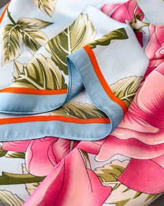 Detail of silk-satin scarf showing pink rose floral print and orange stitched edges