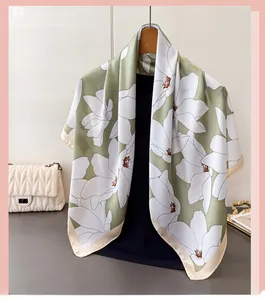 Detail of elegant green and white floral satin scarf hanging with a stylish white handbag