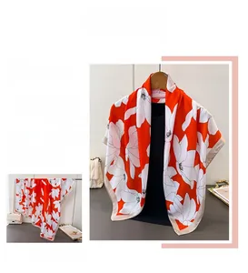 Close-up of orange and white floral print satin scarf with golden hemmed edges