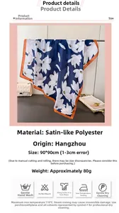 Close-up of 90x90cm satin silk scarf featuring white floral prints and orange borders