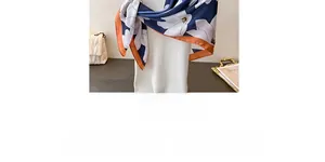 Detail of navy blue satin scarf with white floral print and orange contrast border