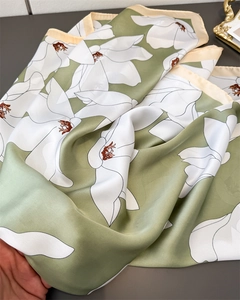 Detail of avocado green satin scarf with white magnolia print and fine hemmed edges