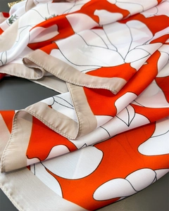 Detail of silk satin scarf showing orange floral pattern and premium stitched edges