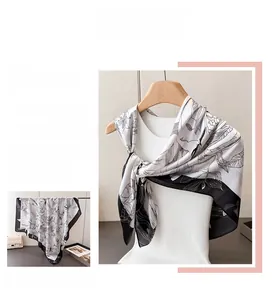 Detailed view of artistic floral satin scarf showing silk texture and black flower prints