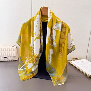 Élégant foulard en satin jaune à motif floral drapé sur un pull bleu marine et cintre