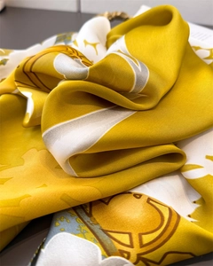 Détail du foulard en soie satinée jaune et blanc avec motifs floraux élégants