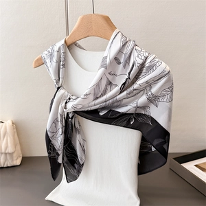Artistic floral print satin silk scarf with black borders elegantly draped on a hanger