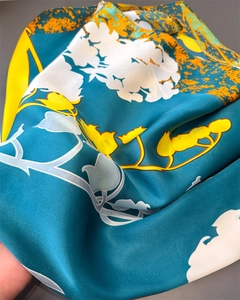 Détail montrant la texture satinée brillante et l'imprimé floral vif du foulard en soie