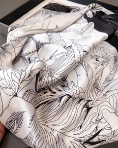 Close-up of artistic floral sketch print on smooth satin silk square scarf texture