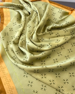 Detailtextur von Seidenschal mit grünen Blumenmustern und orangefarbenem Rautenrand