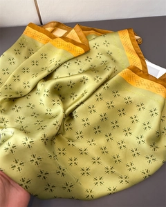 Detail eines Seidensatintuchs mit grünem Sternenmuster und orangem Randdekor