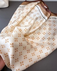 Detail eines seidenähnlichen Satinschals mit orangefarbenem Blumenmuster und dunklem Rand