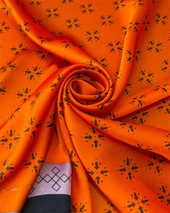 Nahaufnahme der orangefarbenen Seidenschal-Struktur mit floralen Mustern und Glanz