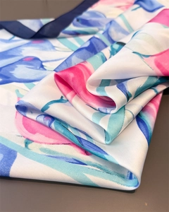 Close-up of silk satin scarf featuring abstract floral prints and dark blue hem edges