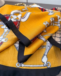 Detail of yellow silk scarf featuring equestrian bridle print and herringbone texture