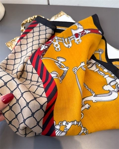 Macro detail of silk-like neckerchief showing herringbone texture and equestrian chain pattern