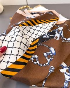 Detail of vintage luxury silk scarf with herringbone pattern and gold chain print design
