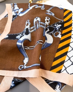 Detailed view of dark brown silk-like scarf with vintage equestrian bit patterns and glossy texture
