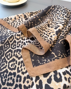 Close-up of leopard print scarf with brown herringbone border and soft woven texture