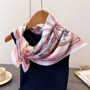 Detail of pink and purple silk scarf with equestrian patterns on a black vest and hanger