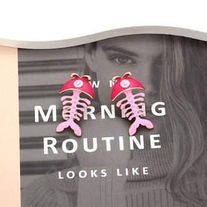Cute pink and red enamel fishbone earrings with diamonds on a stylish magazine background