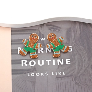 Detailed view of gingerbread man earrings with brown rhinestones and festive enamel dots