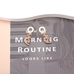 Minimalist gold alloy earrings with white pearls and enamel on a magazine background