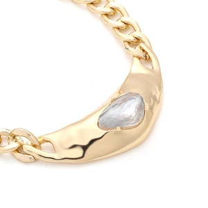 Close-up of gold chain necklace featuring an irregular pendant with a teardrop crystal