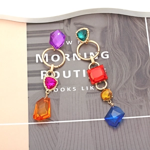 Close-up of asymmetrical long drop earrings with colorful crystals and gold metal rings