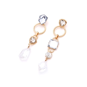 Macro detail of asymmetric gold teardrop earrings with multi-shape clear crystal elements
