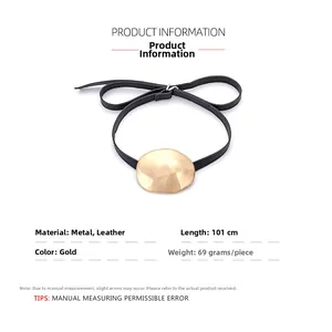 Detail view of golden irregular metal pendant on long black leather cord necklace
