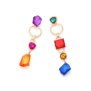 Macro shot of asymmetric drop earrings with colorful crystals and gold-tone metal links