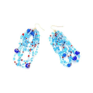 Detail of handmade beaded tassel earrings with blue floral beads and golden hooks