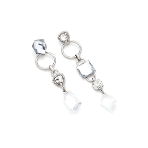 Detailed macro view of asymmetric long drop earrings with clear faceted crystal charms