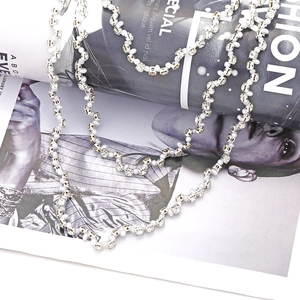 Layered faux pearl and rhinestone necklace displayed on a fashion magazine background