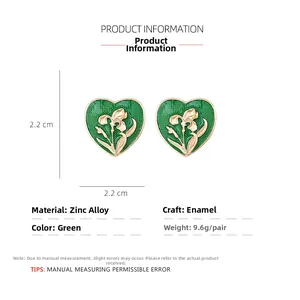 Detail of green enamel heart earrings featuring gold floral relief and zinc alloy frame